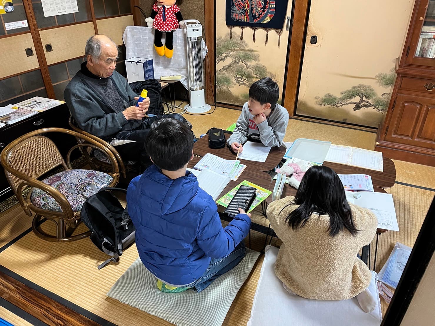 古民家の畳の部屋でお年寄りと子どもたちが一緒に学ぶ様子
